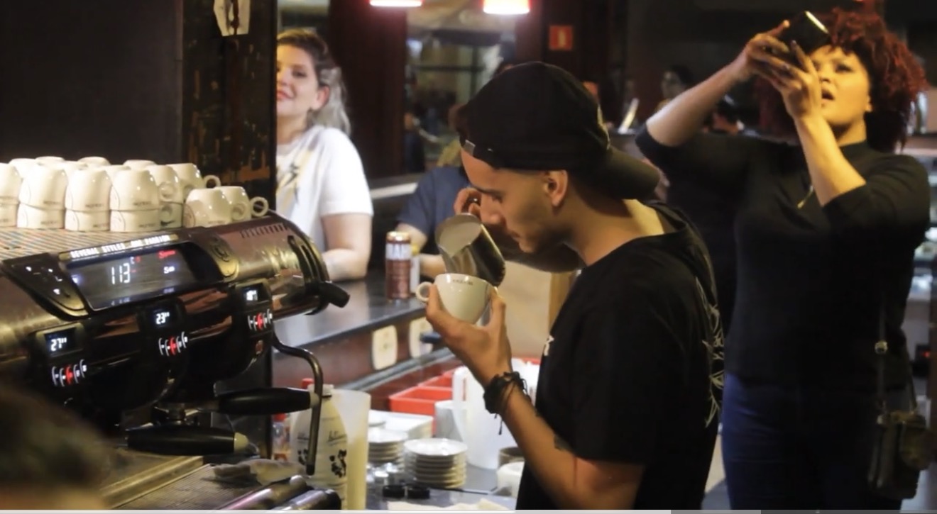 Willen competing — pouring latte art on a professional espresso machine